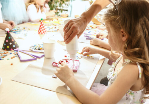 The mosaic puzzle art for kids, children's creative game. The hands are playing mosaic at table. Colorful multi-colored details close up. Creativity, children's development and learning concept